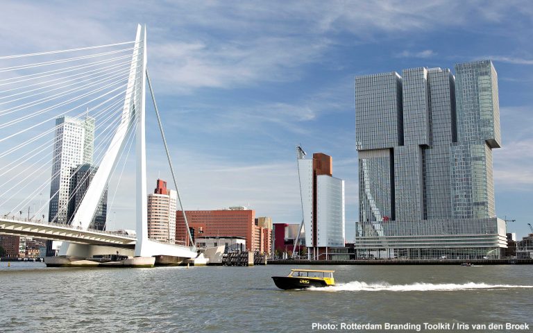 Erasmus bridge and The Rotterdam building, in front a watertaxi on the Maas